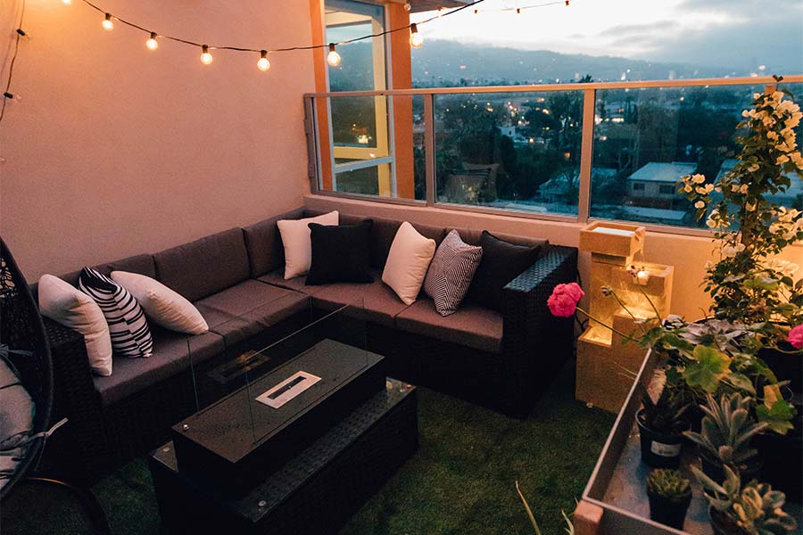 outdoor-sitting-area-in-loft-style-apartment-black-leather-couch-hanging-lights-turf-carpeting