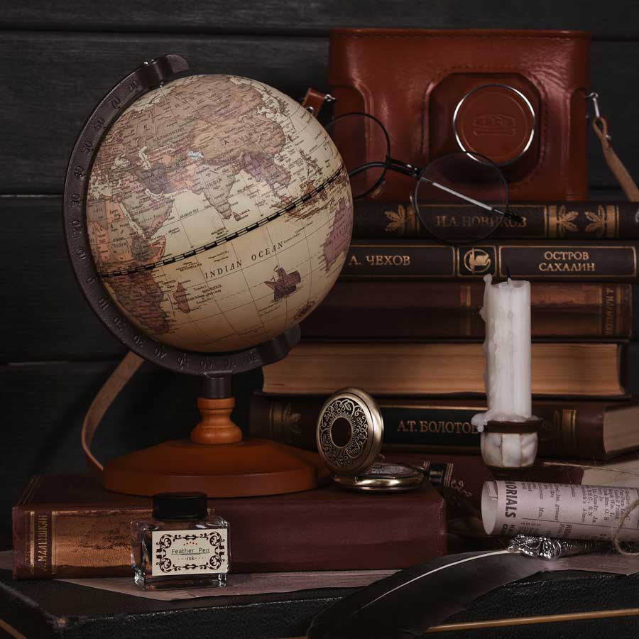 old-world-globe-leather-bag-pocket-watch-half-burnt-candle-all-resting-on-dark-wood-desk-review-for-decluttering
