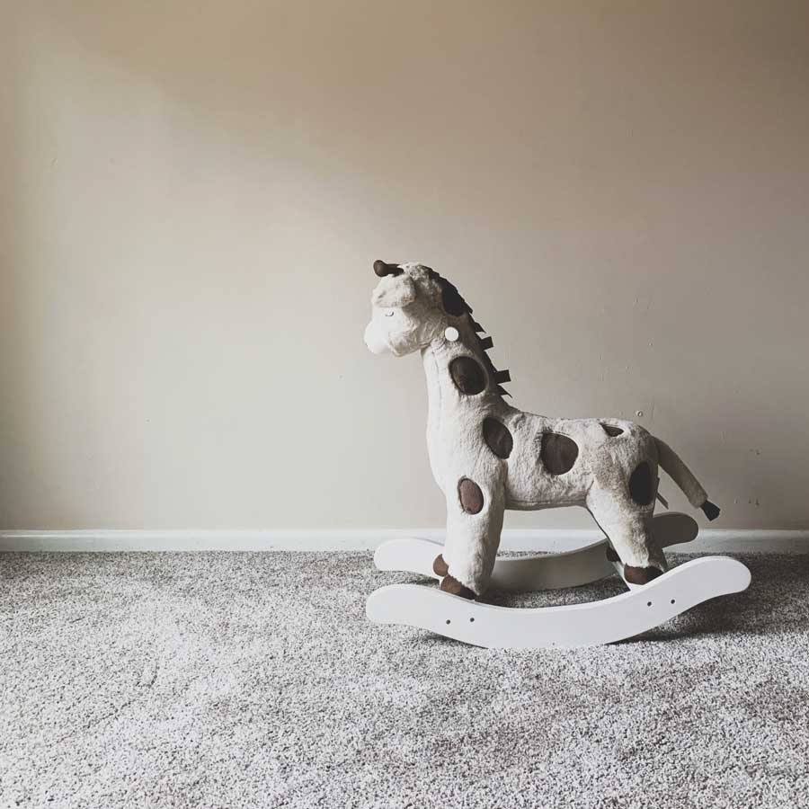 donating-used-childrens-toy-rocking-horse-on-light-gray-carpet-off-white-walls