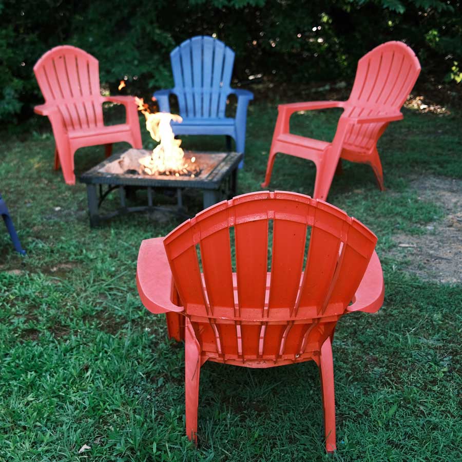 red-pink-bluei-colored-lawn-chairs-circling-fire-pit-in-backyard