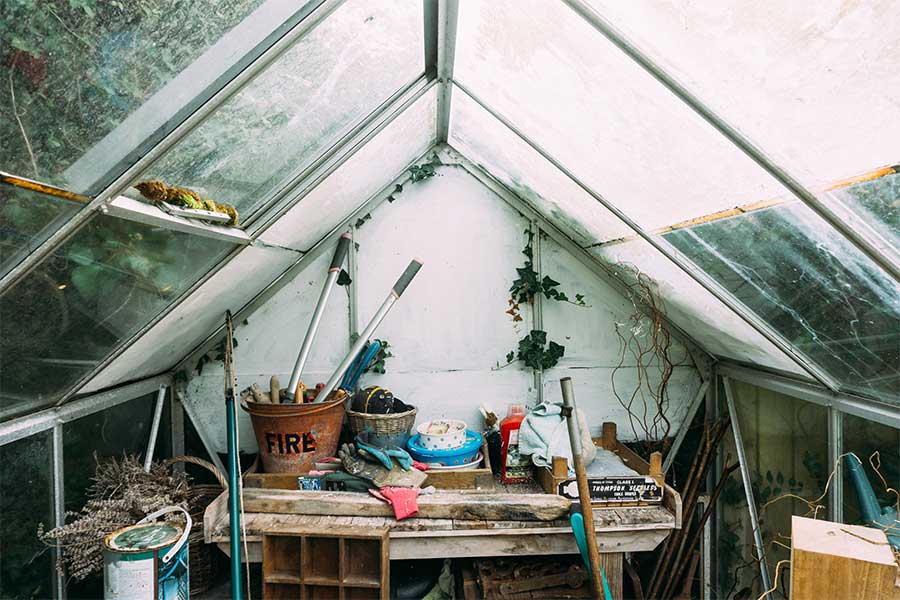 cluttered-shed-interior-daytime-tools-flower-pots-mop-glass-roof-greenhouse