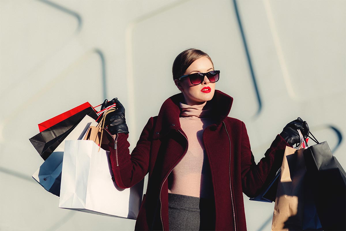 woman wearing designer coat carrying several fancy shopping bags | Personal concierge services by The Personal Helpers