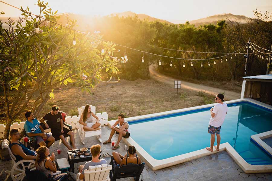 summer party ideas for home backyard area with pool and people sitting around on outdoor furniture